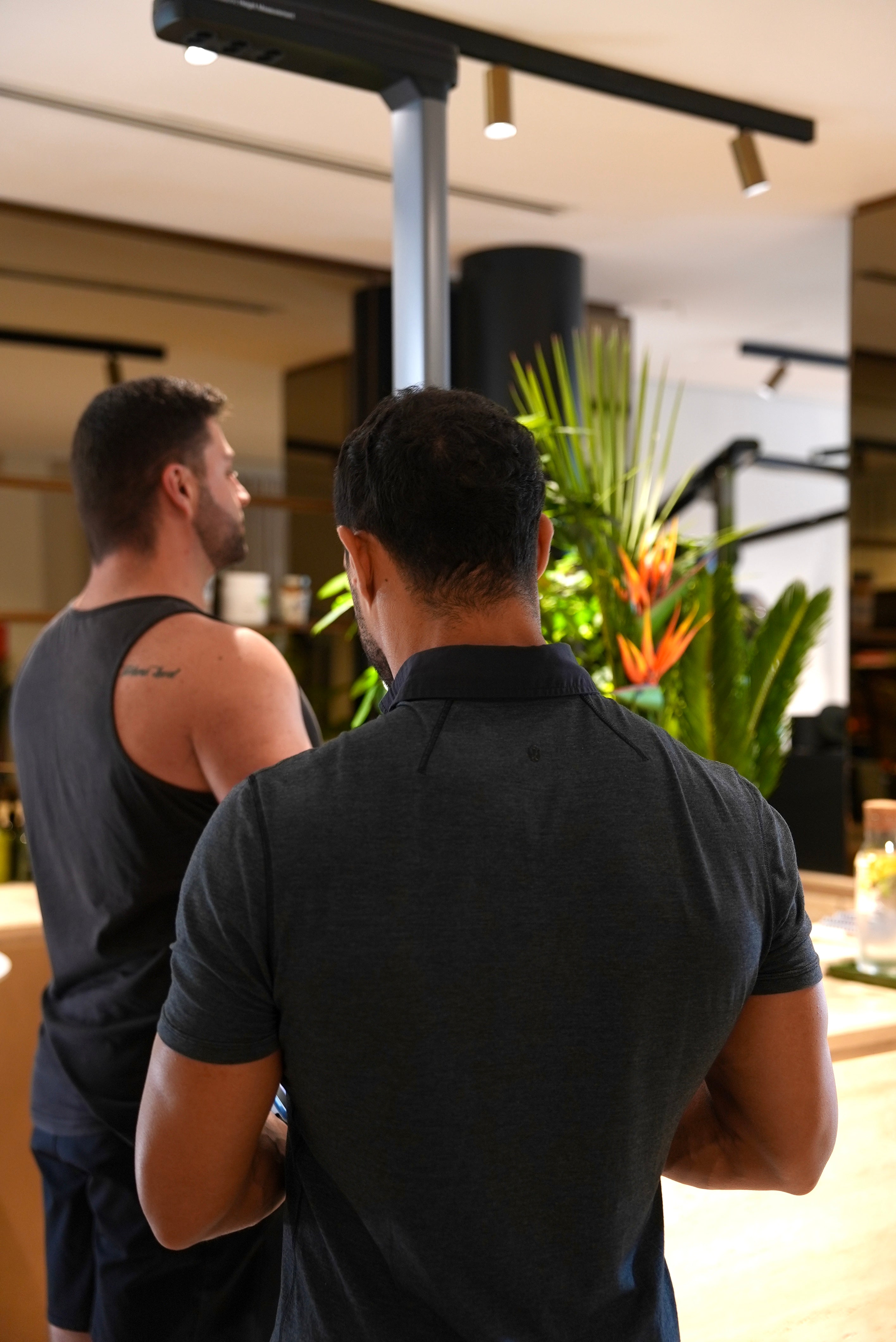 Personal trainer guiding client through a body composition measurement session in a green calm designer gym environment.