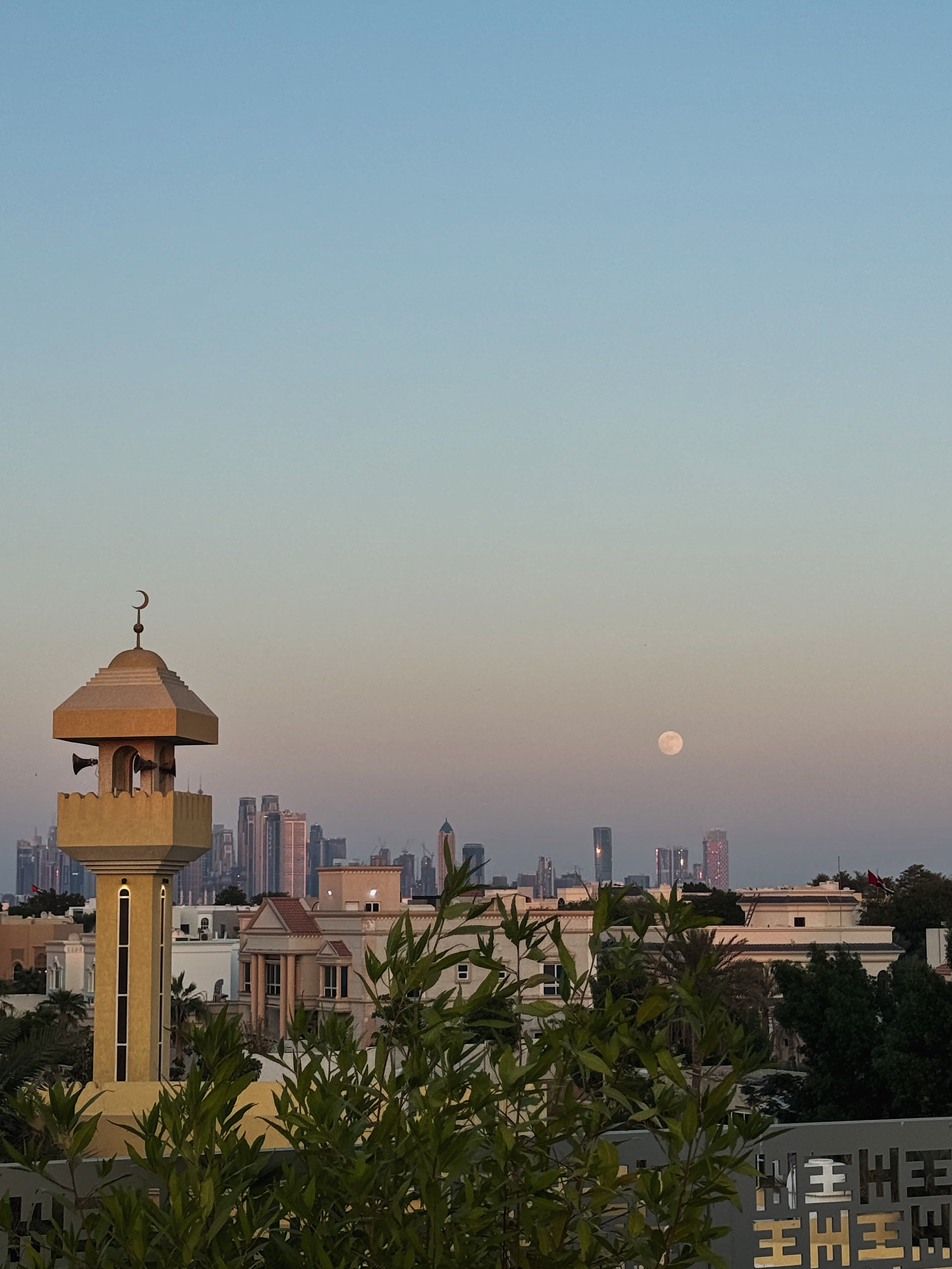 Minaret with Dubai city skyline and full moon in the background, a view from the Halm Collective rooftop, Jumeirah Dubai.