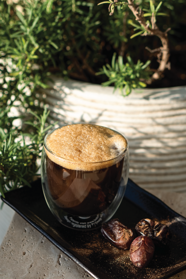 Swedish Salted Coffee served outside on a tray on a glass cup with a side of dates. From the Halm Cafe menu, Jumeirah, Dubai.