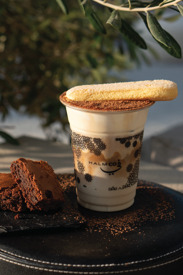 Tiramisu luxe frappe served with lady biscuit, whipped cream and chocolate powder. Served in a takeaway cup to stay or takeaway from the Halm Cafe menu, Jumeirah, Dubai.