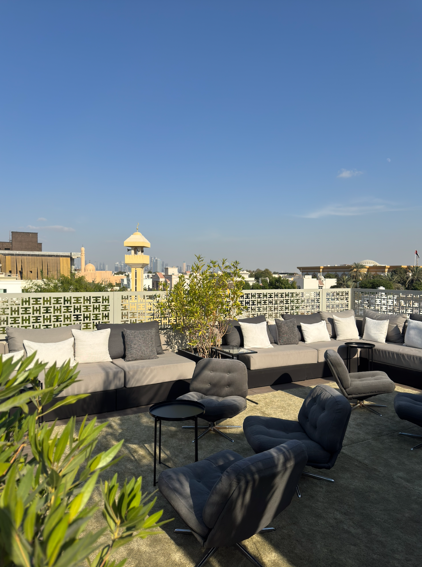 Outdoor rooftop lounge majlis area with modern furniture and Dubai cityscape in the background.