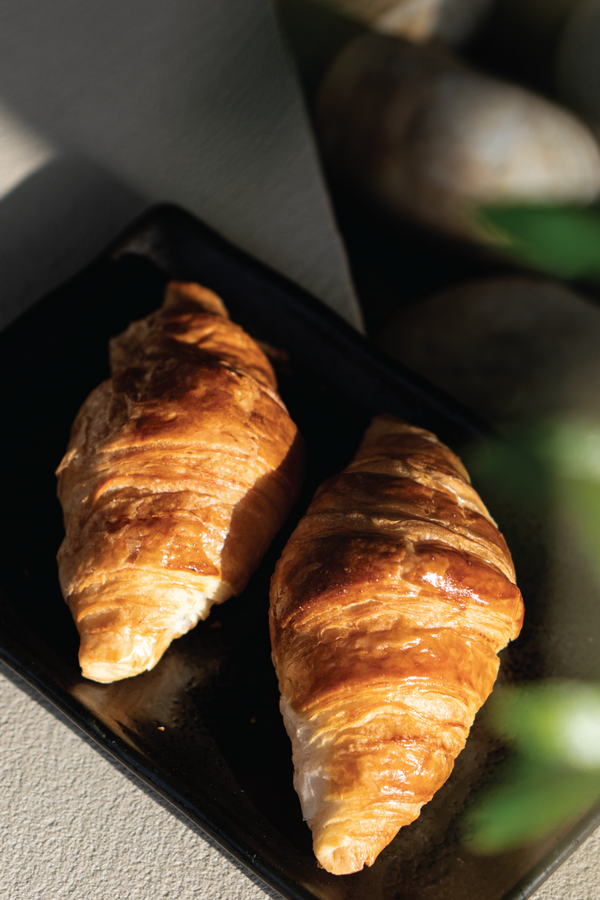 Two croissants on a black plate served outdoors to enjoy at Halm Cafe, Jumeirah, Dubai.