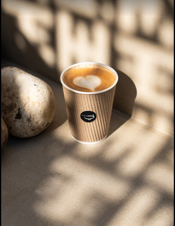 Cup of coffee with a heart design on a stone surface with natural light casting shadows. Takeaway Coffee, Jumeirah Beach Road.