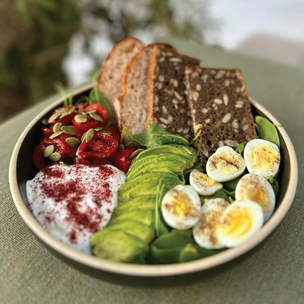 Avacado, zaatar feta, quail eggs, tomatoes, pumpkin seeds and pomegranate served with infused sourdough and rye bread in a bowl. From the Halm Cafe menu, Jumeirah, Dubai.
