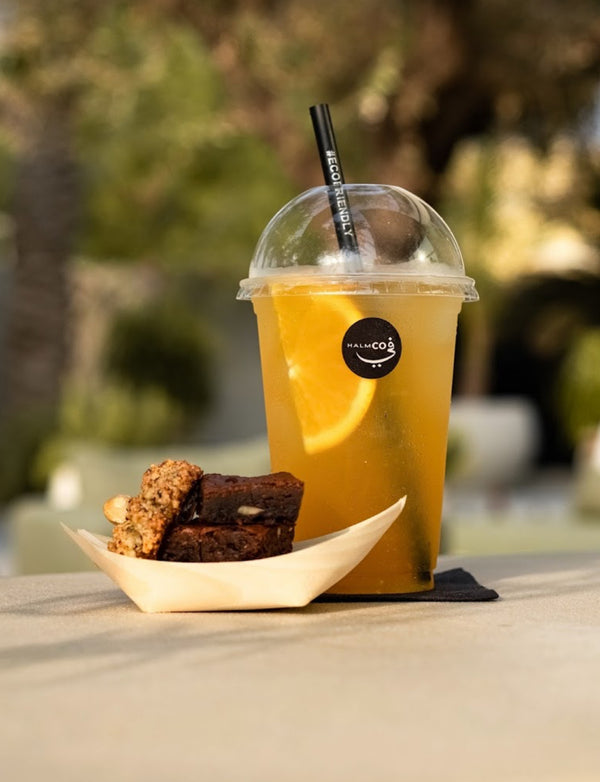 Homemade iced tea flavour Bamboo Snow White served with a straw and snacks on a table outdoors.