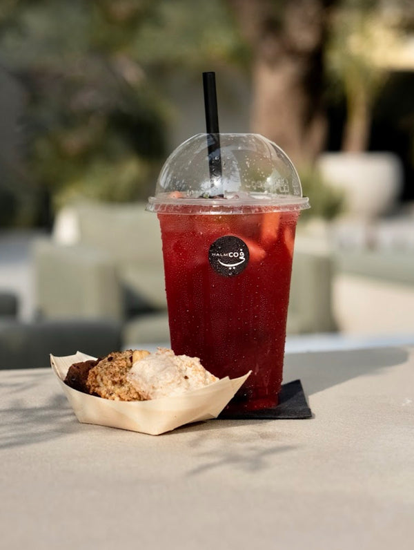 Homemade ice tea oriental with a straw and a pastry on a table outdoors.