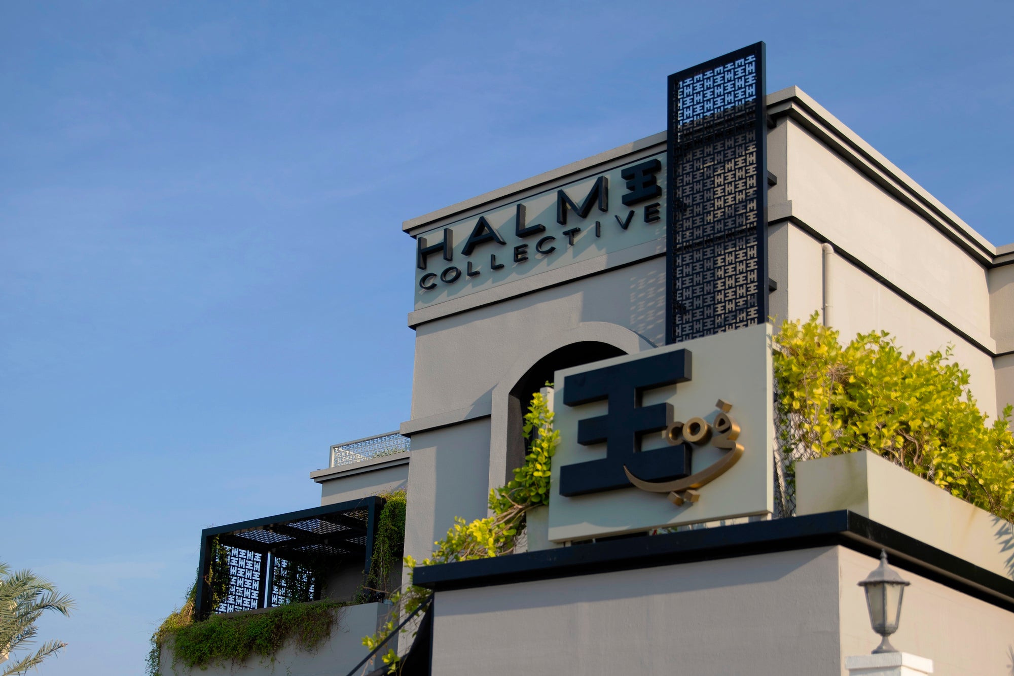 Halm Collective black linen coloured villa and green garden outside view with iconic Halm black branding mashrabiya.