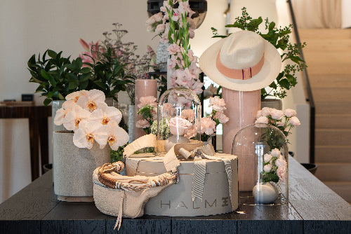 Decorative table with pastel coloured flowers, handmade panama hat, luxury Halm limited edition leather handbags and accessories in soft colours from the curated concept store at Halm Collective, Umm Suqeim.