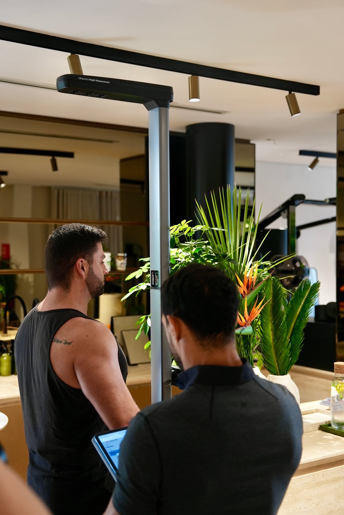 One-to-one fitness assessment—trainer checks client metrics on a body-composition scanner in a boutique Dubai gym