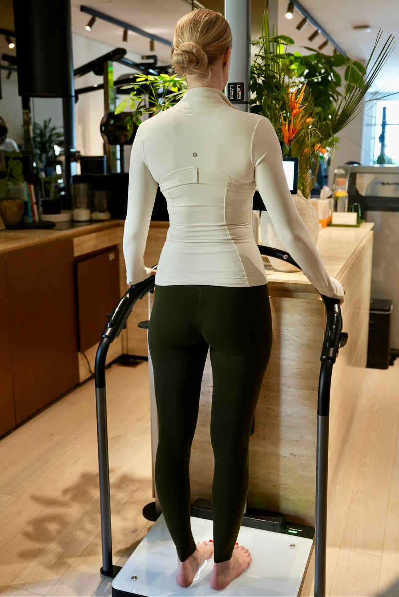 Female using a body composition analysis machine iindoors at Halm Collective Wellness Club. 
