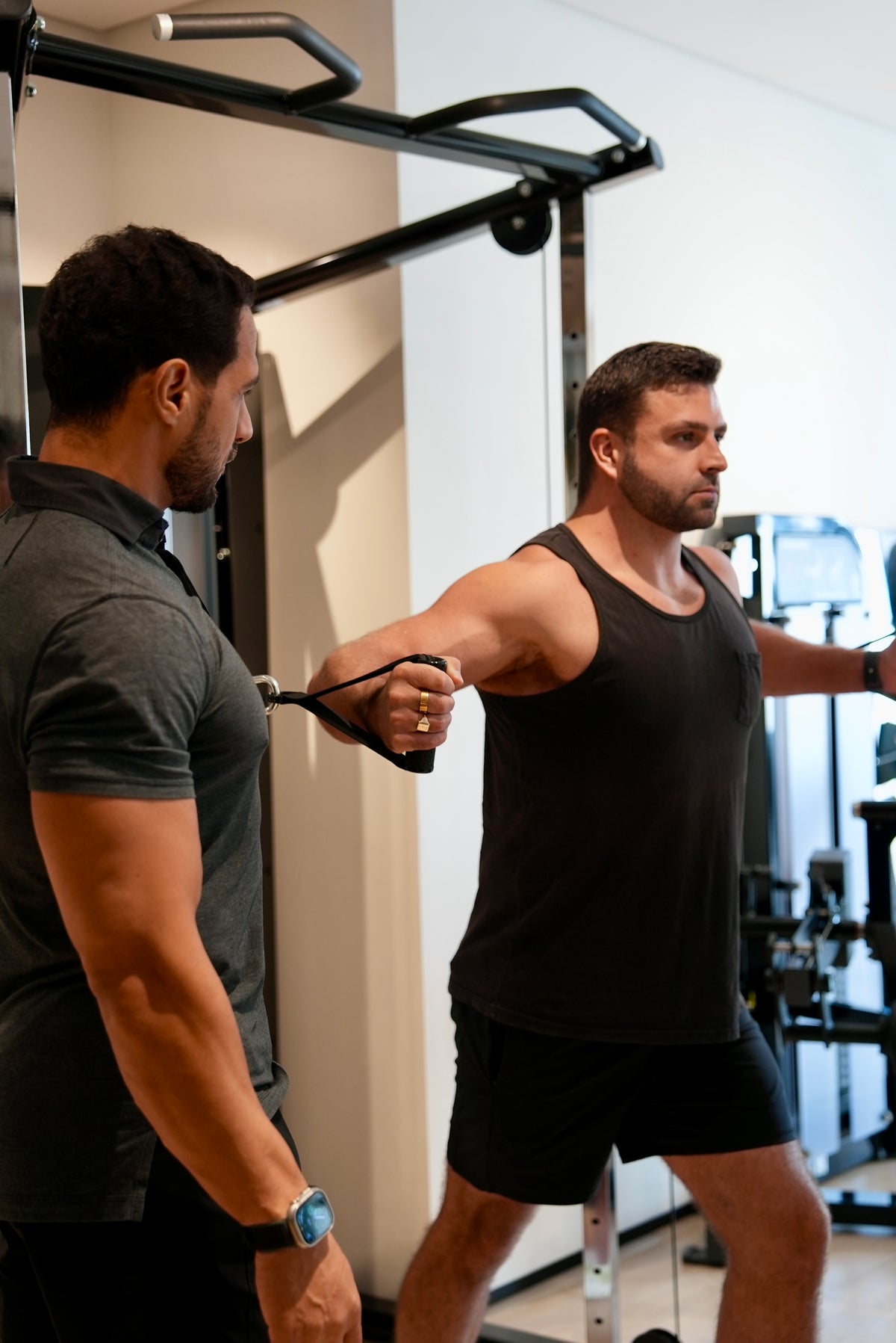 One-on-one strength training client performing cable fly with a coach in a private Jumeirah, Dubai gym