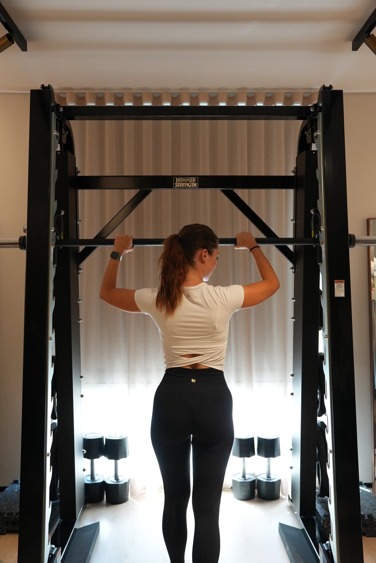 Personal trainer performing a barbell exercise on a Smith machine in a wellness club gym in Jumeirah Dubai. 