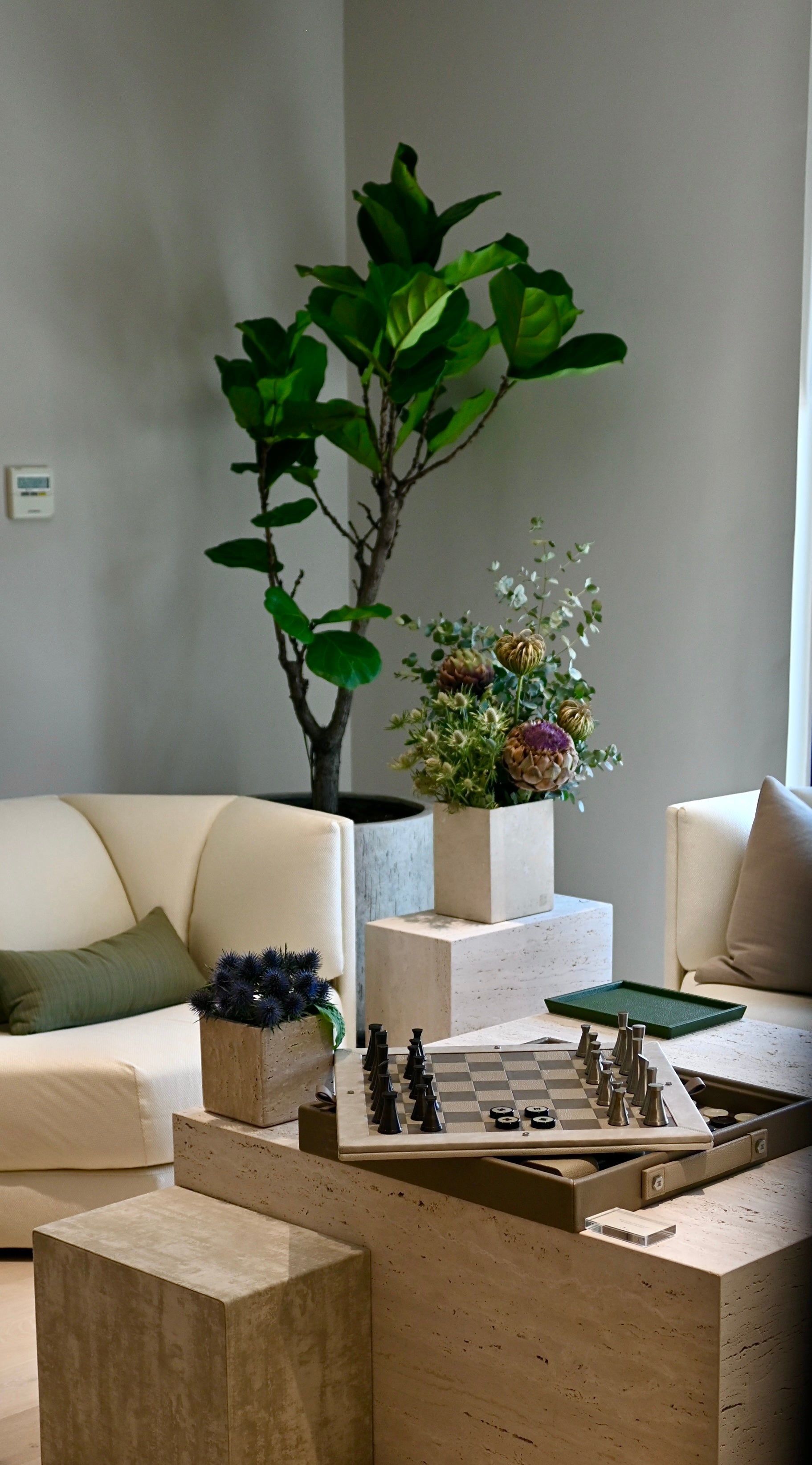 Elegant wellness club lounge with neutral-toned Halm designed seatings, green indoor fig plants and floral decor. 